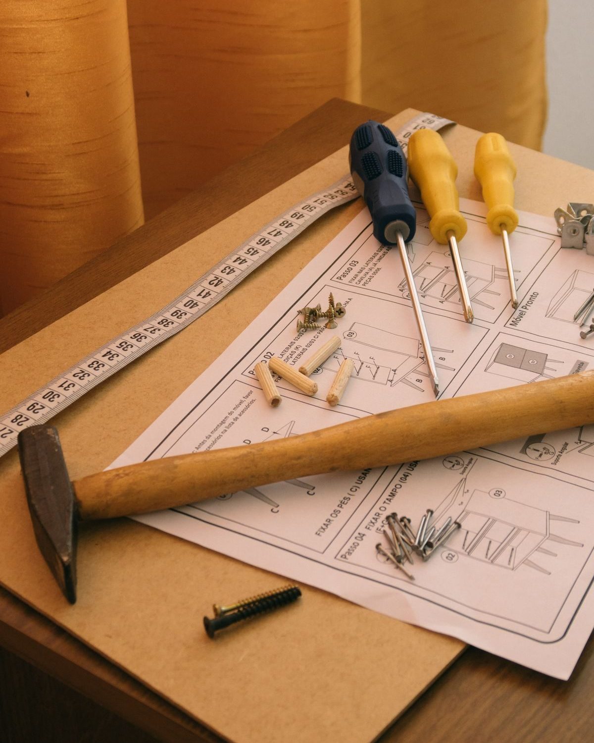 Screws, fittings and an instruction sheet next to a screwdriver and a tape measure
