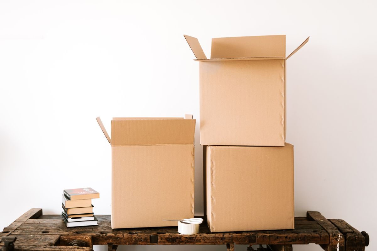 Cardboard boxes and a stack of books on a wooden table