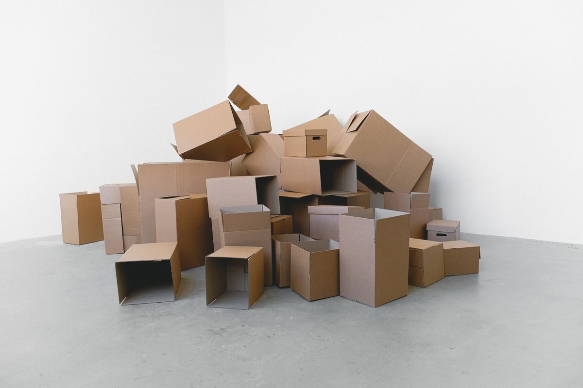 A pile of flat and open cardboard boxes on a bare floor